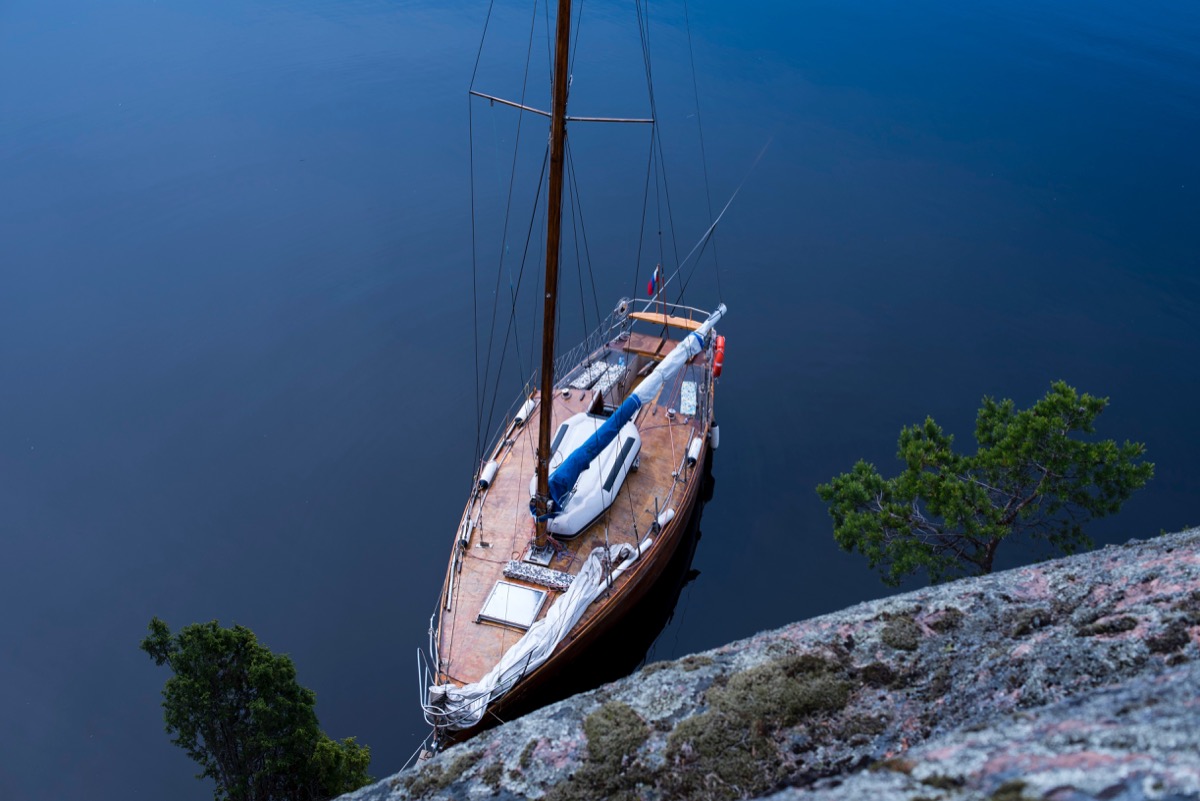 Small sailboat with wooden deck anchored at shore
