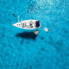 A sailboat at anchor from above in clear blue waters